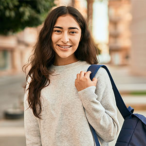 Girl smiling outside holding her backpack